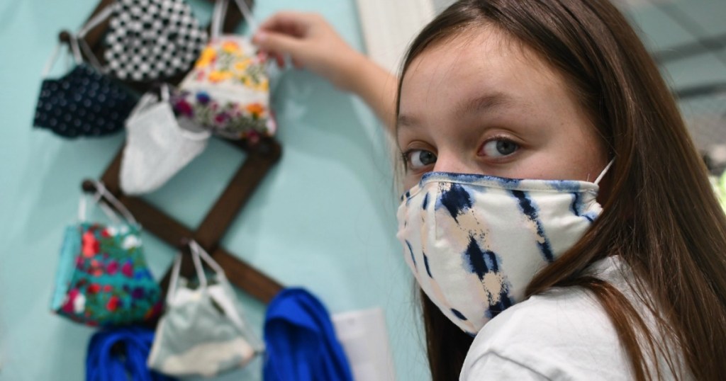 child wearing mask with face mask storage rack in background