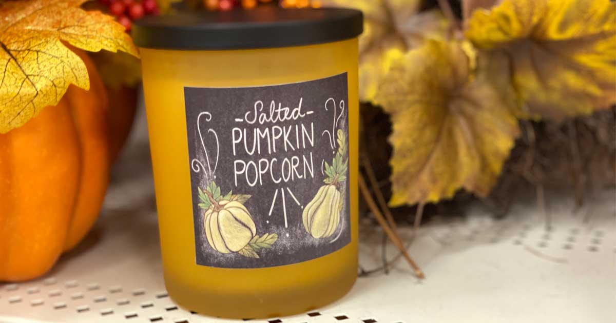fall themed candle nestled around faux fall foliage and pumpkins