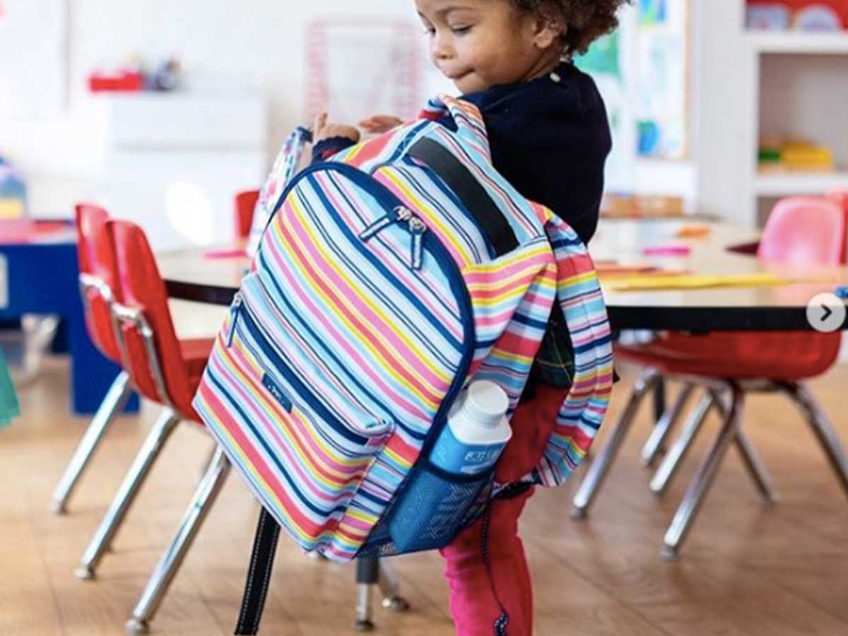 little girl holding scout backpack