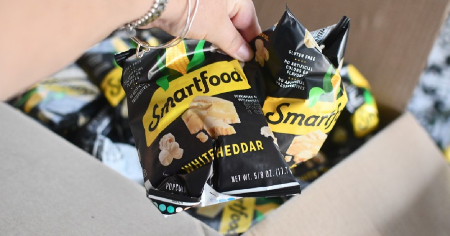 hand holding up two small bags of smartfood popcorn