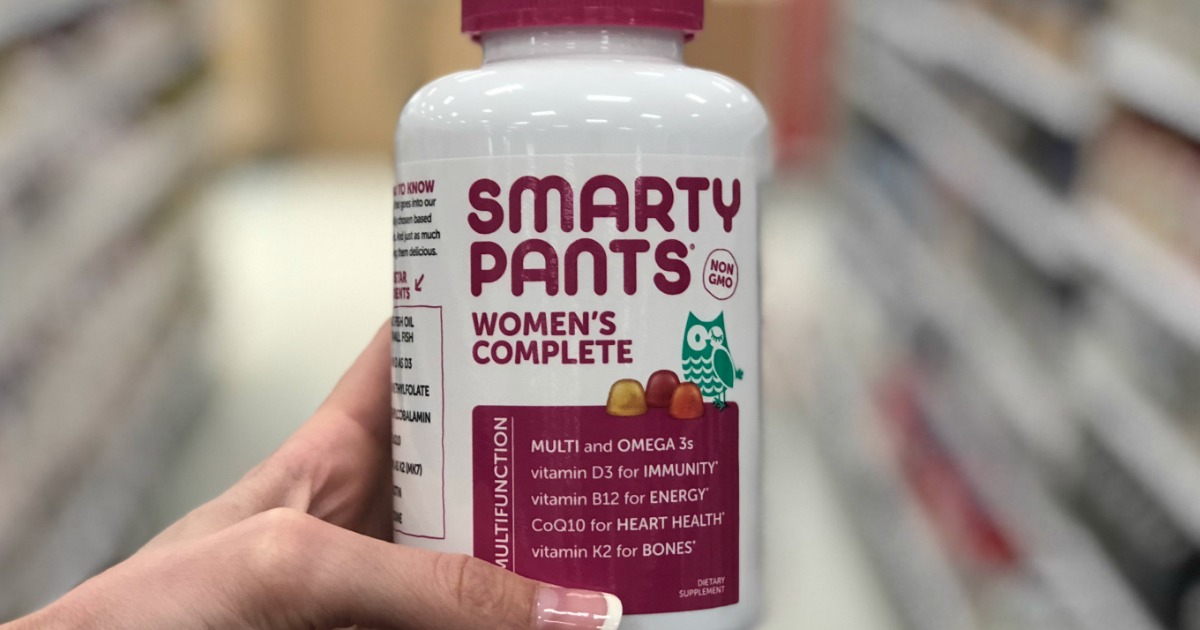 womans hand holding bottle of vitamins in store aisle
