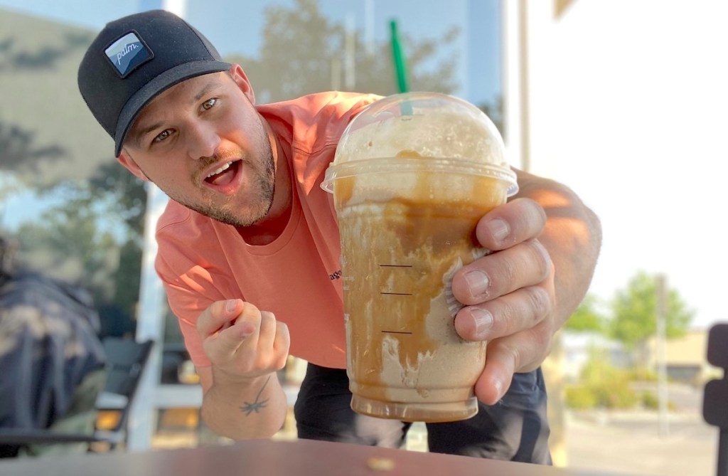 man holding a starbucks snickers frappuccino in hand