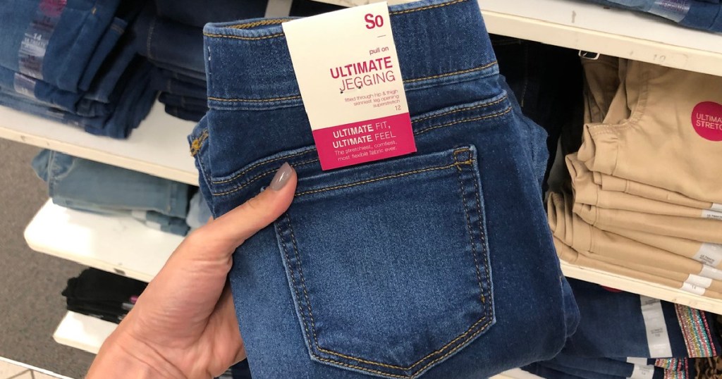 hand holding pair of jeans up by store display