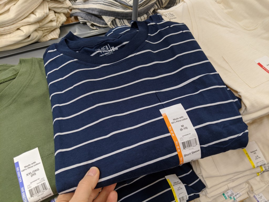 woman's hand on a folded stripe shirt on store display