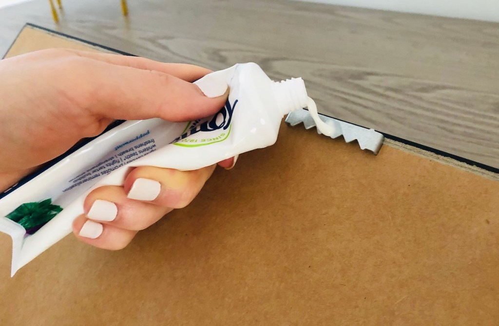 hand holding a tube of toothpaste for how to hang a picture hack