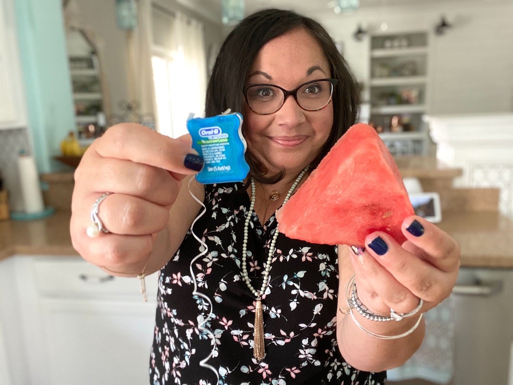 woman holding watermelon wedge and dental floss 