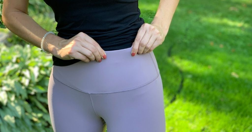 woman pulling on waistband of leggings