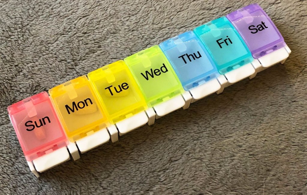 multi-colored weekly pill organizer box on grey fuzzy blanket