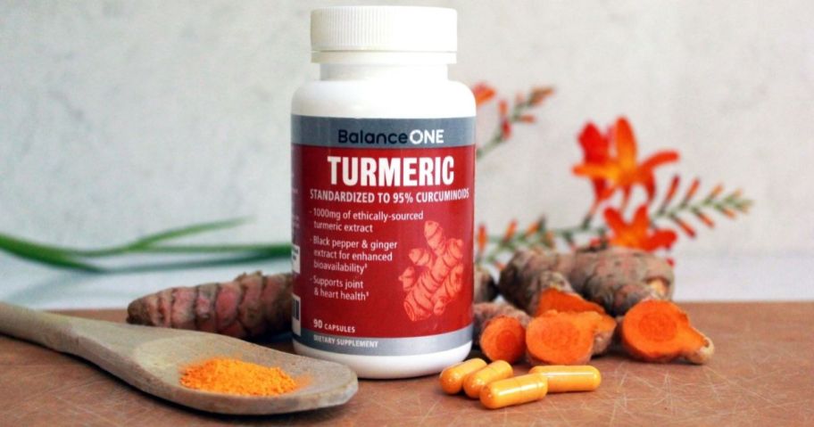 bottle of Turmeric next to spoon and capsules