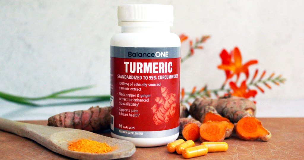 white and red bottle of balance one turmeric capsules on wooden table