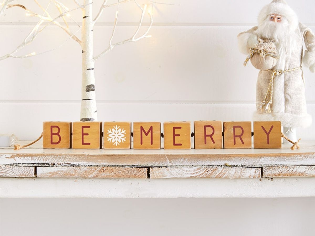 be merry blocks on table top with white snow santa and white tree