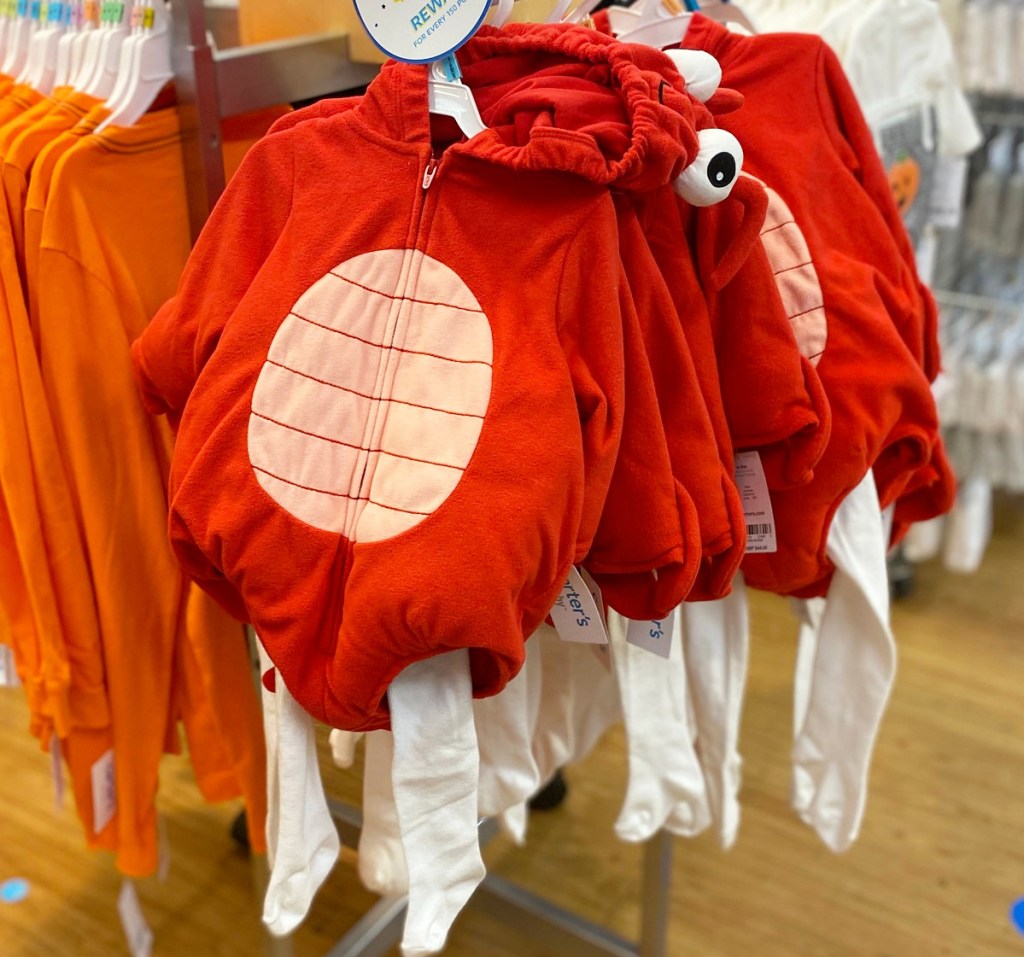red lobster baby costume with white leggings hanging on hangers on store display rack