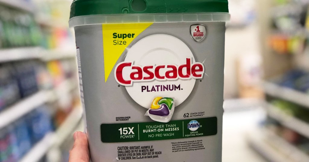 person holding up large grey and green container of cascade dishwasher detergent tablets