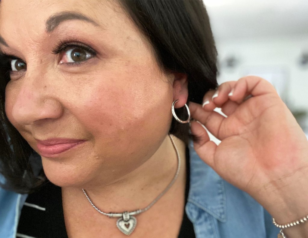 woman with black hair wearing a pair of white gold sparkly hoop earrings