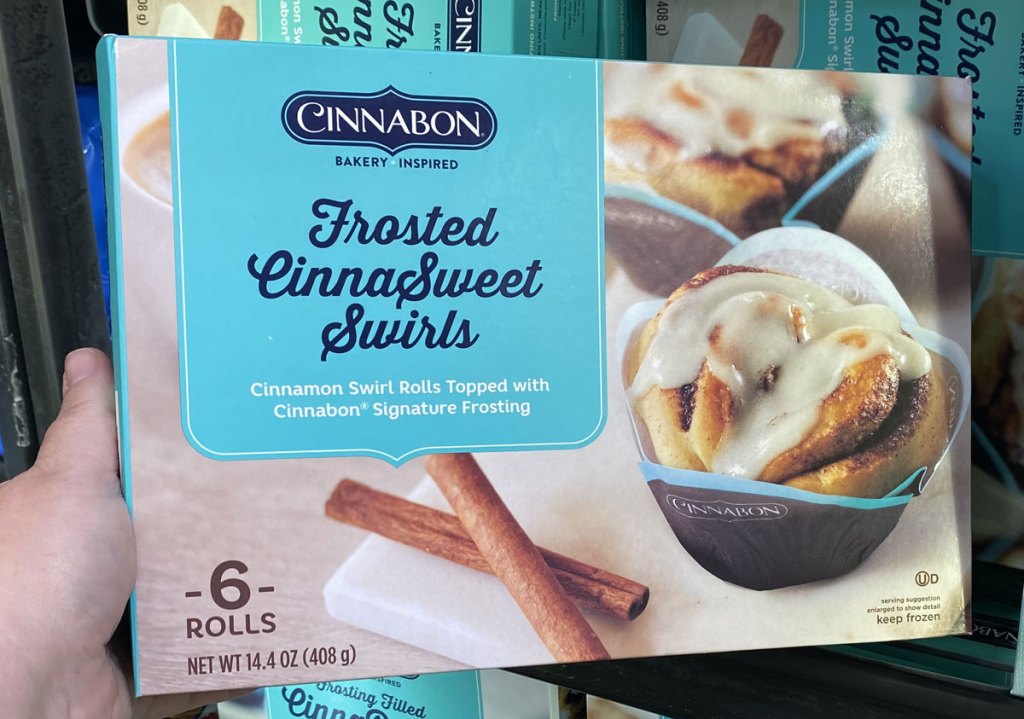 person holding up blue box of Cinnabon frost cinnasweet swirl breakfast pastries
