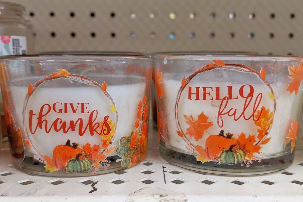 two glass jar candles that say give thanks and hello fall