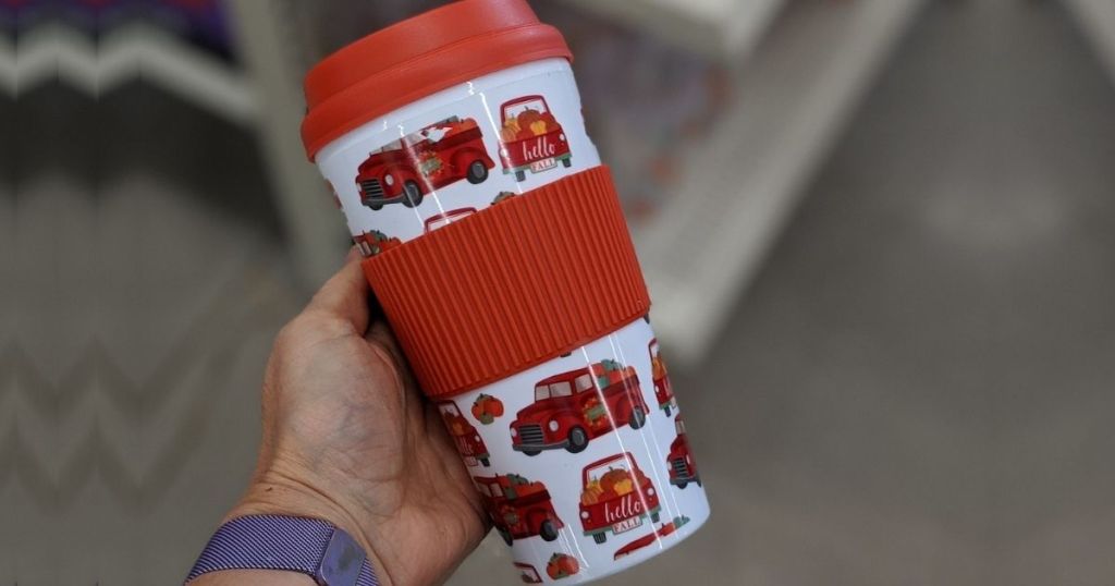 Woman's hand holding a Dollar Tree Tumbler with Fall Vintage Trucks