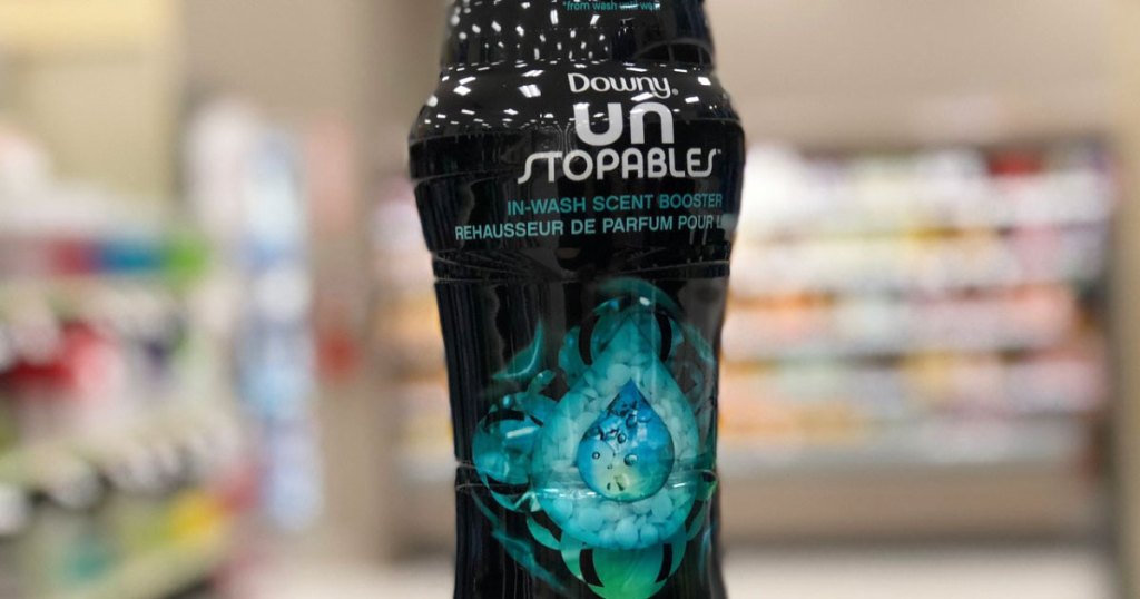 person holding up black and blue bottle of downy unstoppables laundry scent booster beads