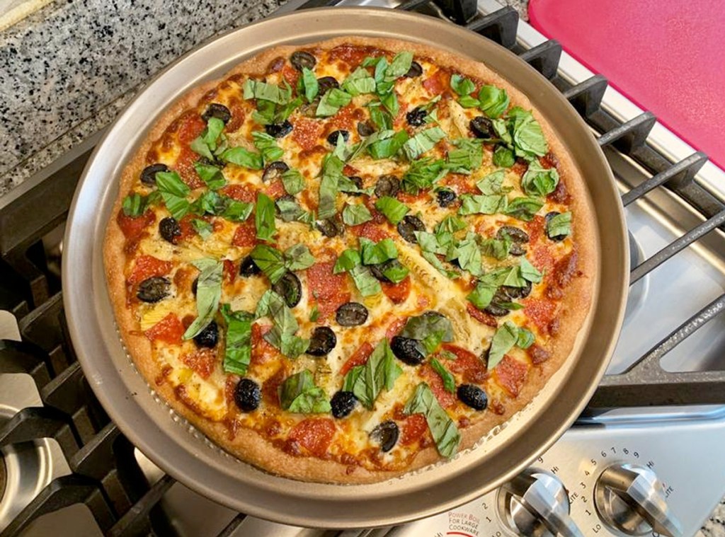 vegetable pizza on a brown pizza pan on top of a stove