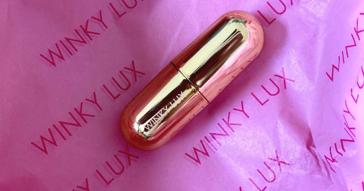 A gold tube of lip balm on pink tissue paper