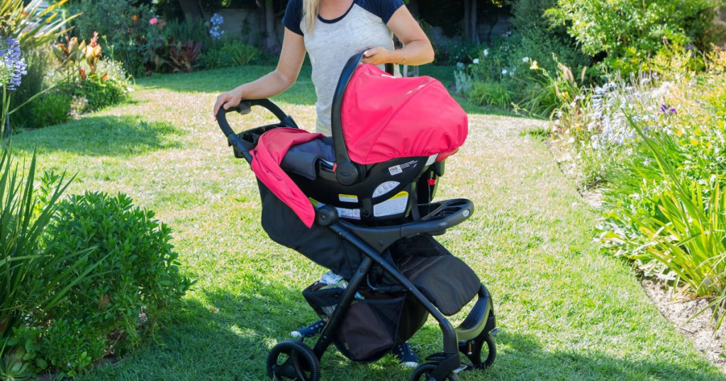 woman standing outside over a bright pink and black care seat stroller system 