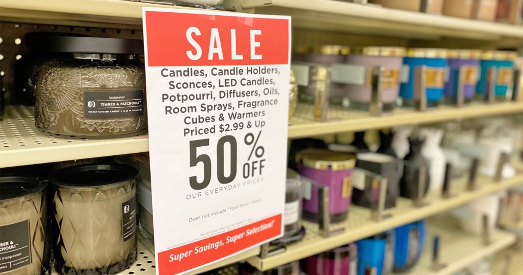 Hobby Lobby candle sale sign on shelf full of glass jar candles