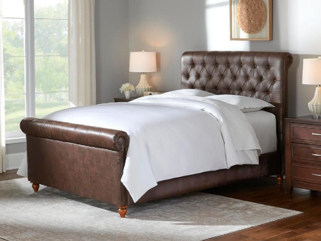 brown leather sleigh bed with white beddingn a bedroom nexto night stands and a lamp