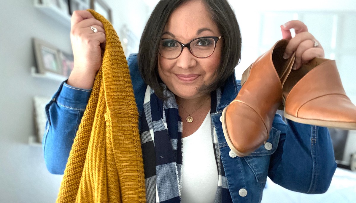 woman holding yellow sweater and brown booties