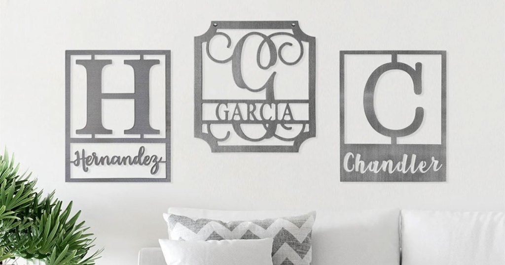 three rectangular steel monogrammed family name plaques on wall above white couch