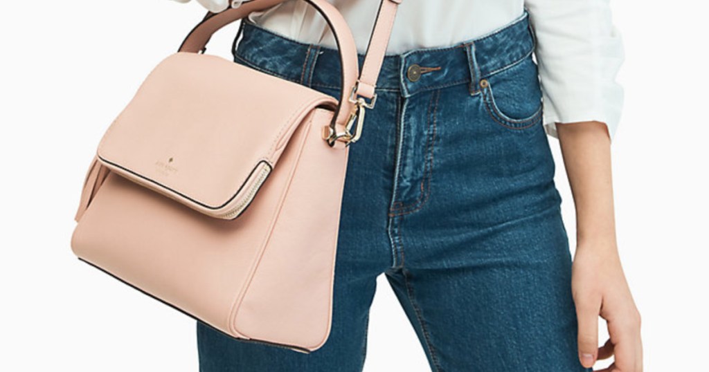 Woman carrying a light pink Kate Spade handbag with a zipper and tassle