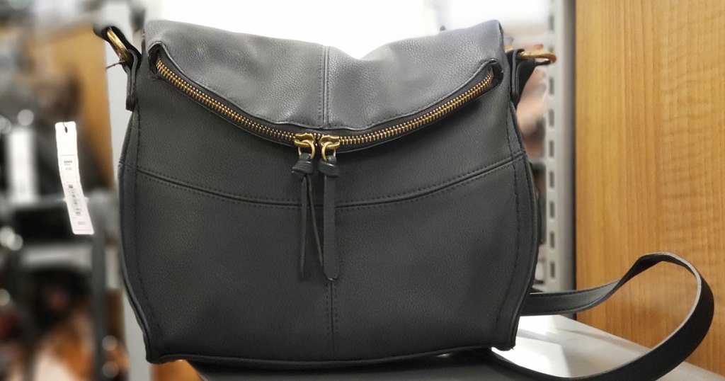 black leather crossbody bag with zipper details on store display shelf
