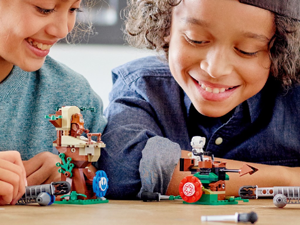 2 kids smiling and playing with a lego star wars playset