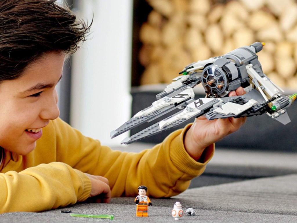 boy playing with a lego star wars tie fighter plane