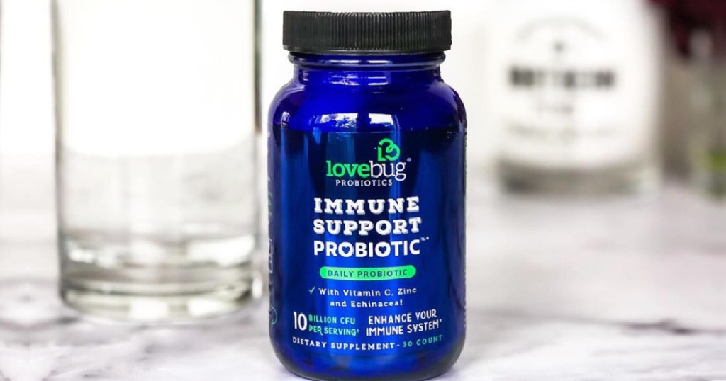 glass jar of Lovebug Probiotic Supplements sitting on a counter next to a glass of water