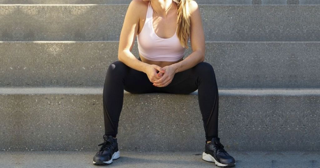 woman sittingon concrete stairs wearing workout clothing