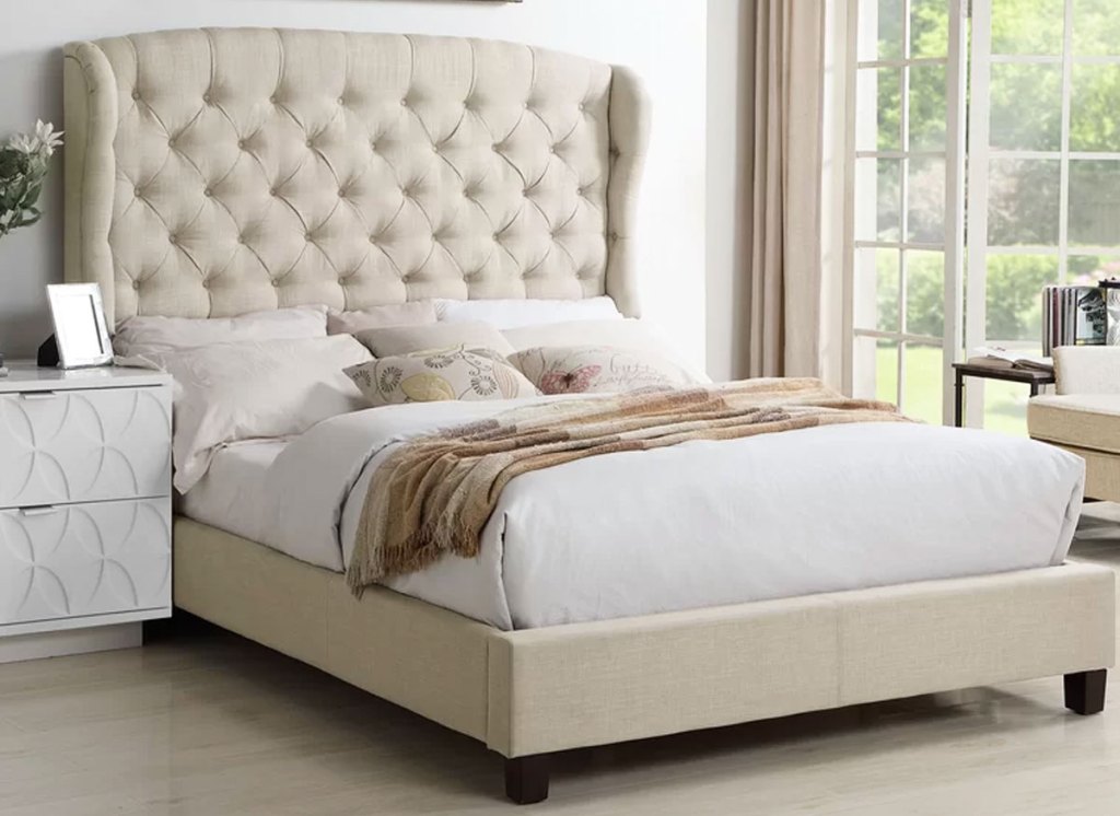 cream colored tuffed upholstered bed with white bedding on top
