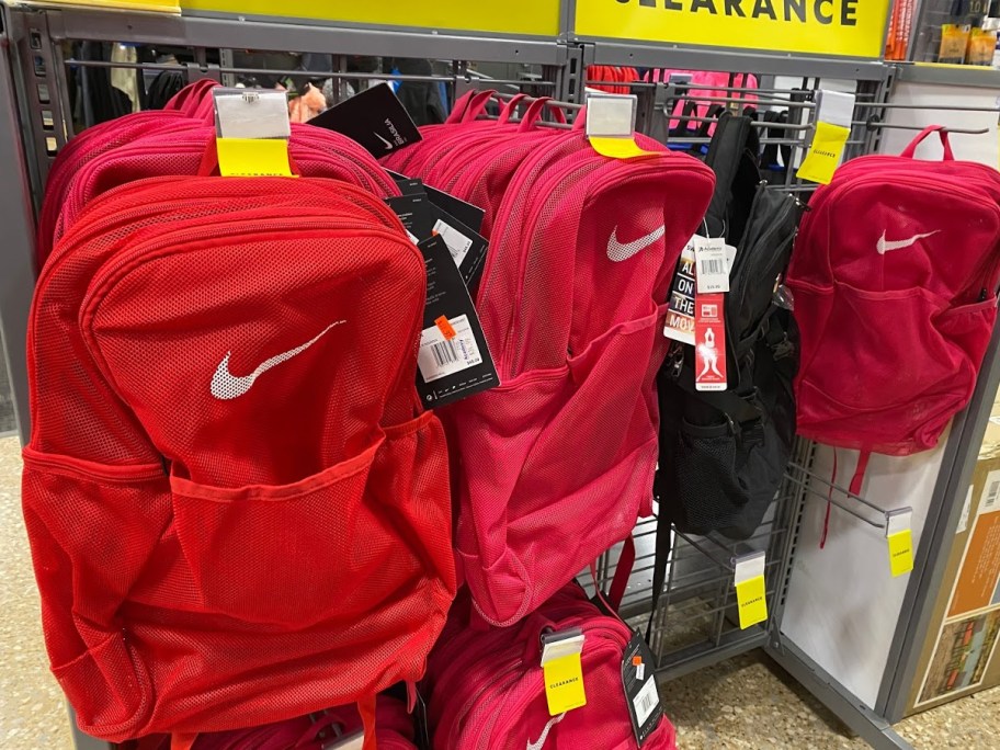 red, pink, and black mesh backpacks hanging in store