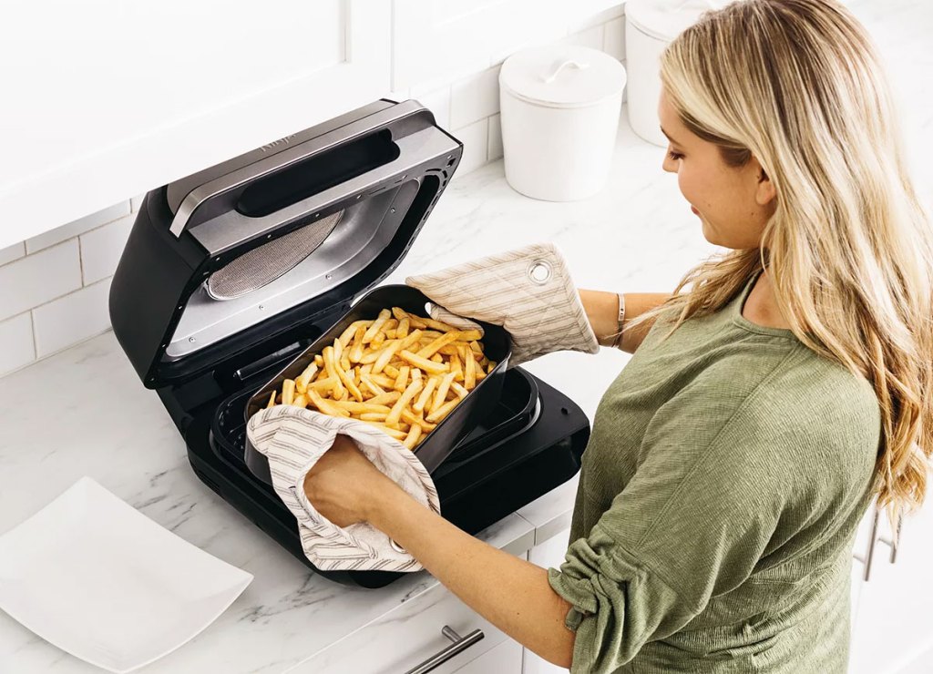 woman removing a basket of french fries from Ninja Foodi grill