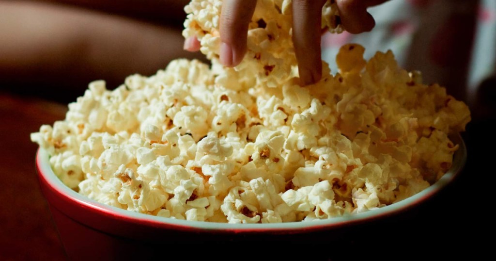 hand grabbing popcorn from bowl