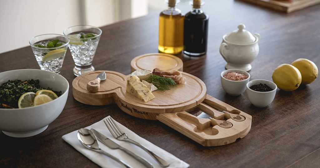 Mickey Mouse shaped cheese board, tools, and food on table