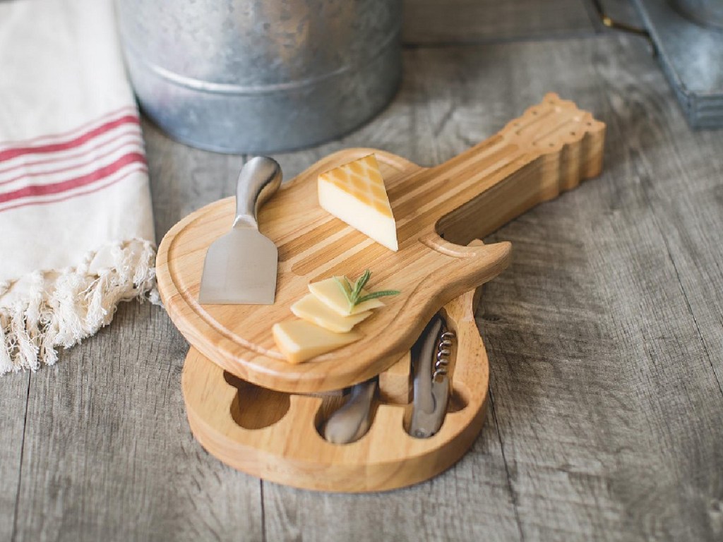 guitar shaped cheese board, tools, and food on table