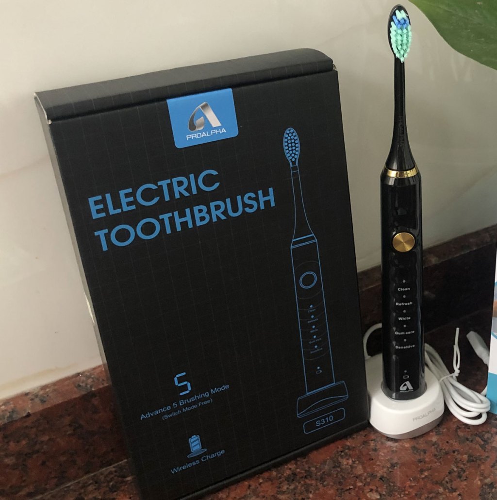 black electric toothbrush on a white charging base with it's box next to it
