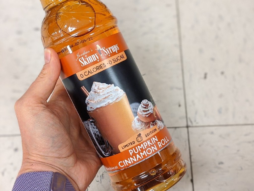 hand holding large bottle of pumpkin cinnamon roll sugar free syrup