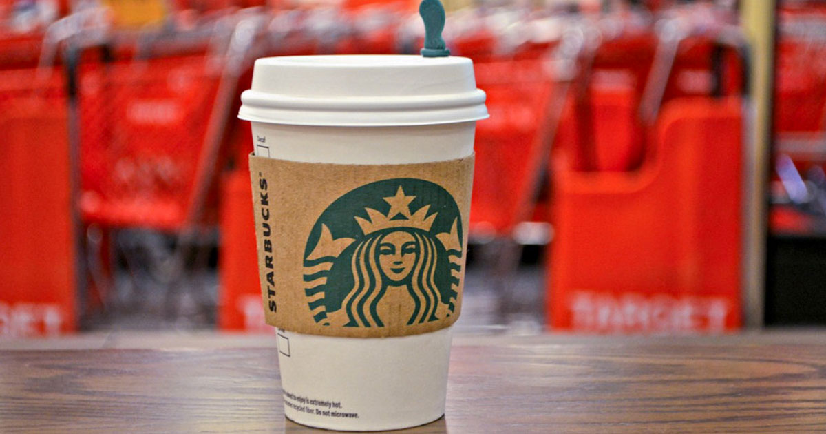 Starbucks hot drink on wood table in front of red Target shopping carts