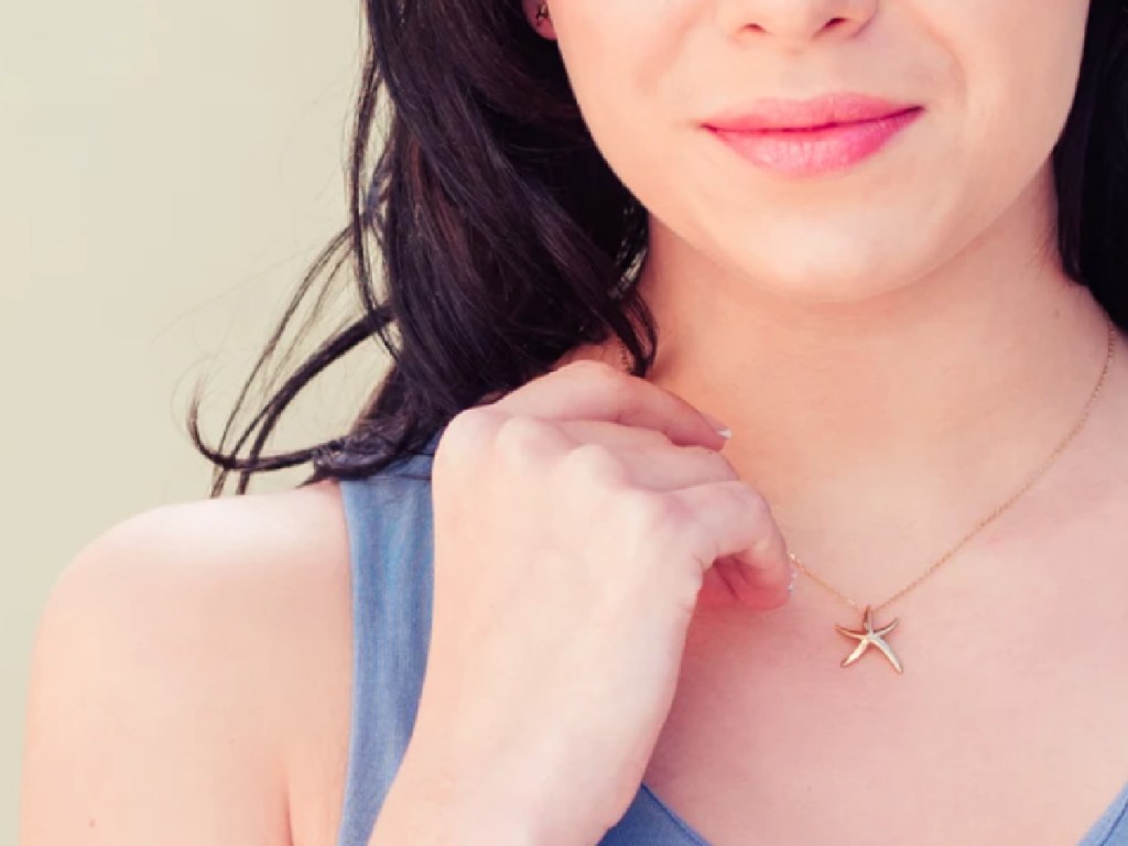 woman with her hand near her neck wearing a gold tone Starfish necklace