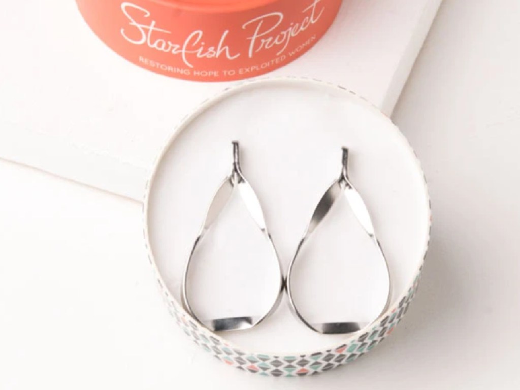 silver teardrop shaped hoop earrings sitting in a box next to an orange lid