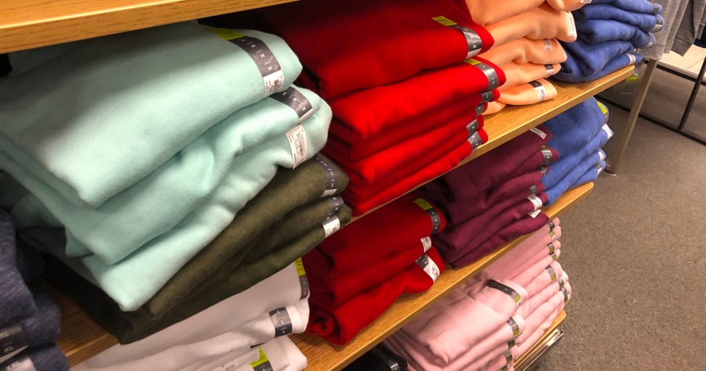 stacks of folded women's sweatshirts on wood display shelves