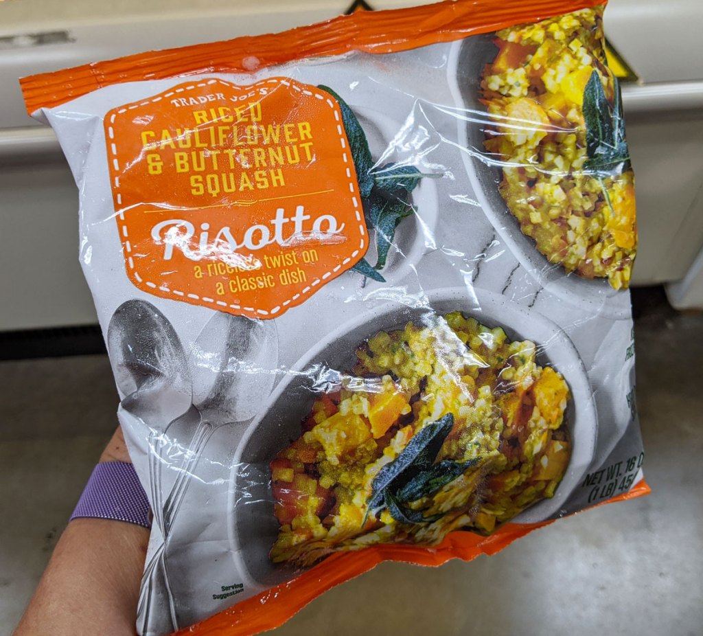 person holding up a bag of frozen riced cauliflower butternut squash risotto meal