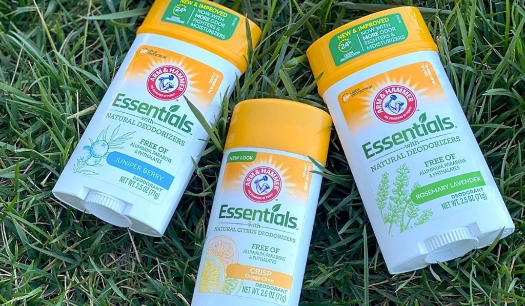 three bottles of arm and hammer deodorant laying on grass