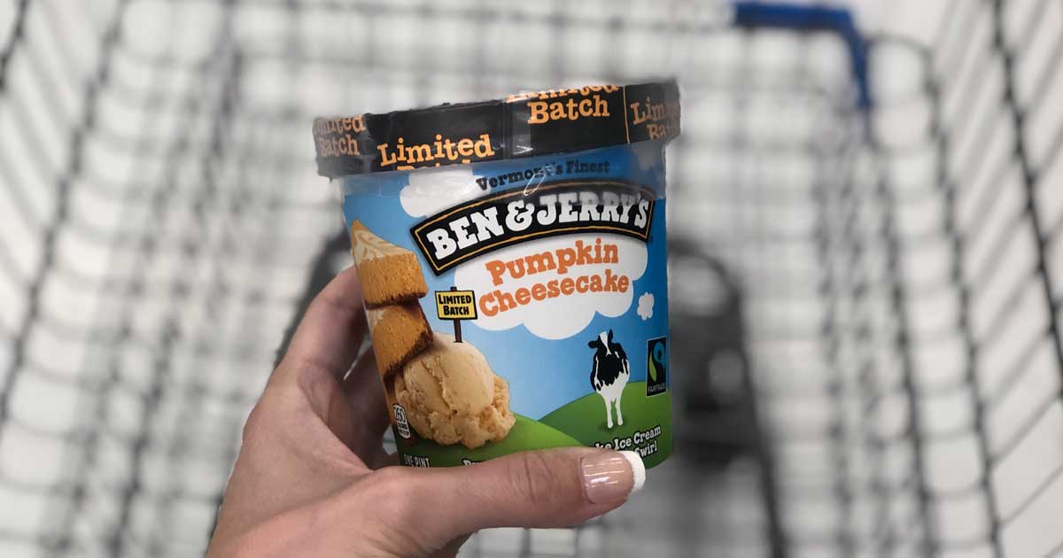 hand holding a pint of pumpkin cheesecake ice cream above a store cart